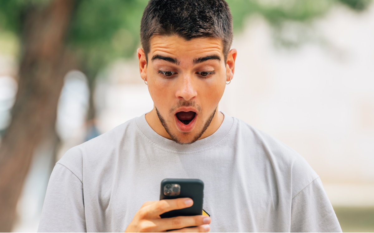 Homme choqué devant son smartphone